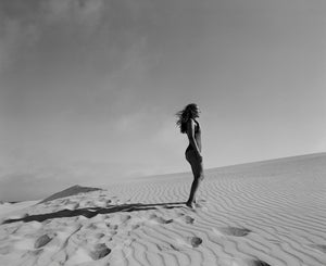 Black and white photo of woman on beach wearing swimsuit
