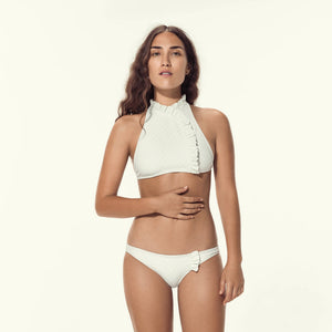 Woman wearing cream two piece swimsuit with ruffle detail